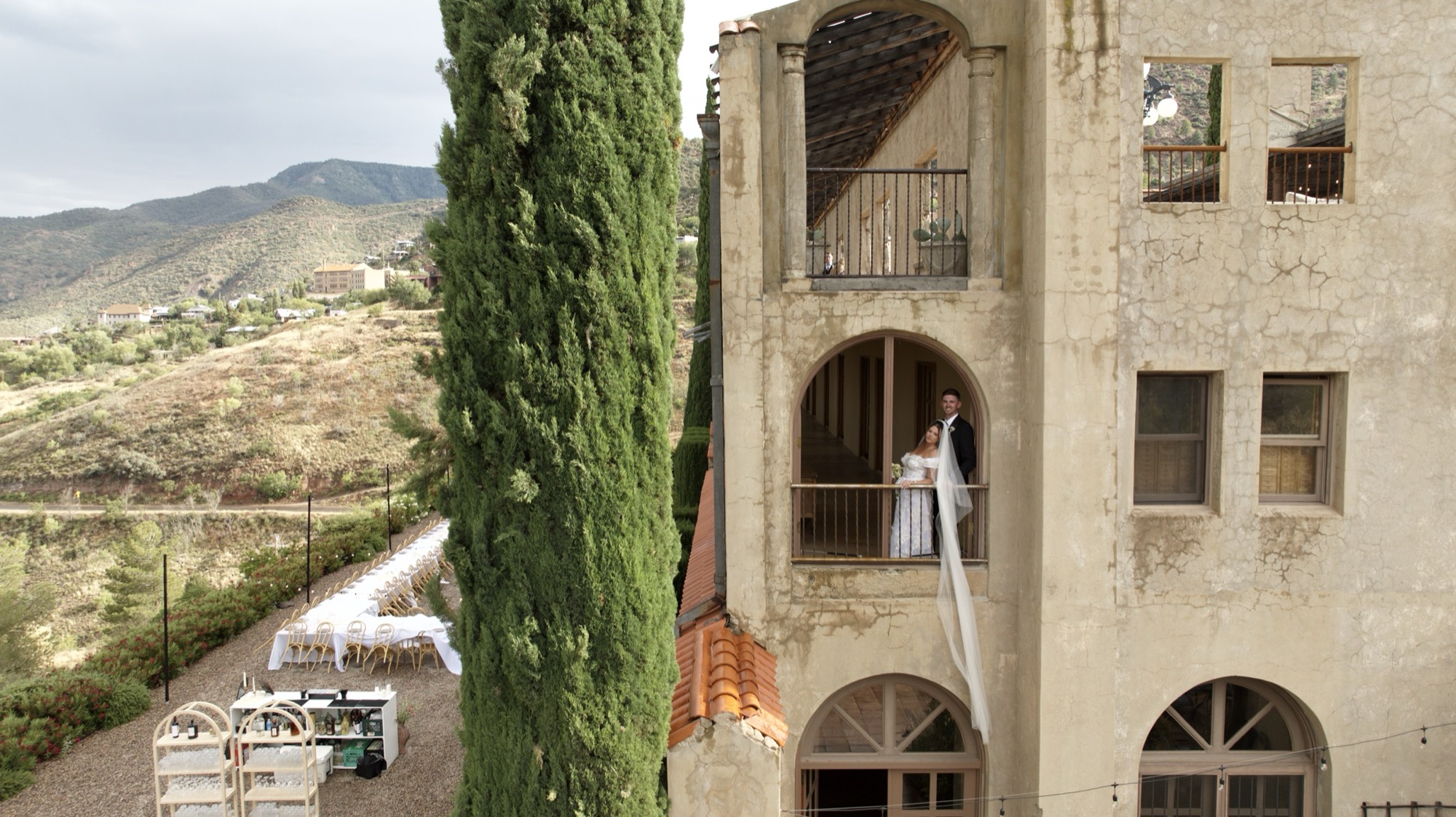Abigail and Ethan together in an arched balcony at The Little Daisy in Jerome, with her veil draped down the façade