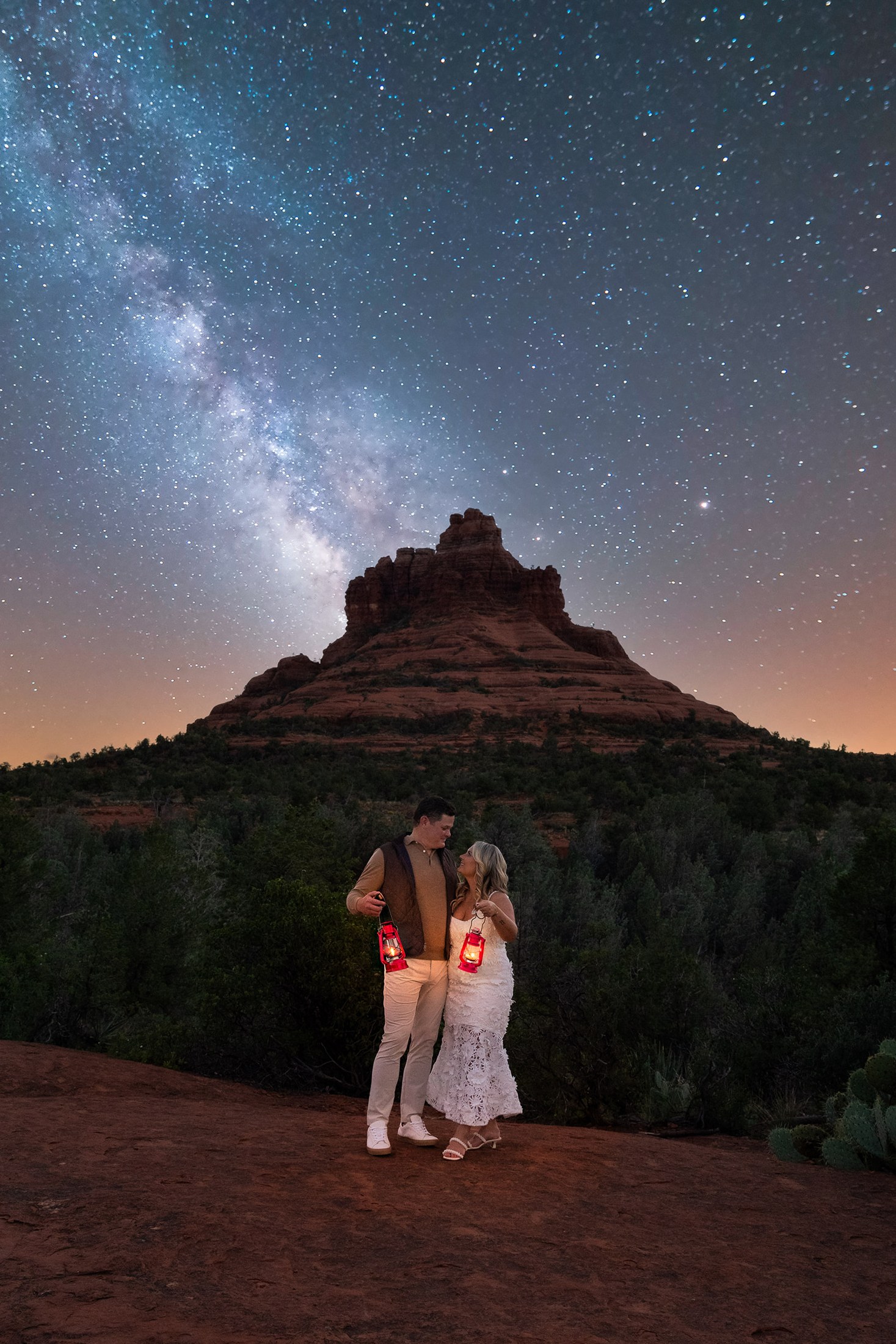 Karly and Jeromy holding lanterns beneath the Milky Way beside Bell Rock in Sedona