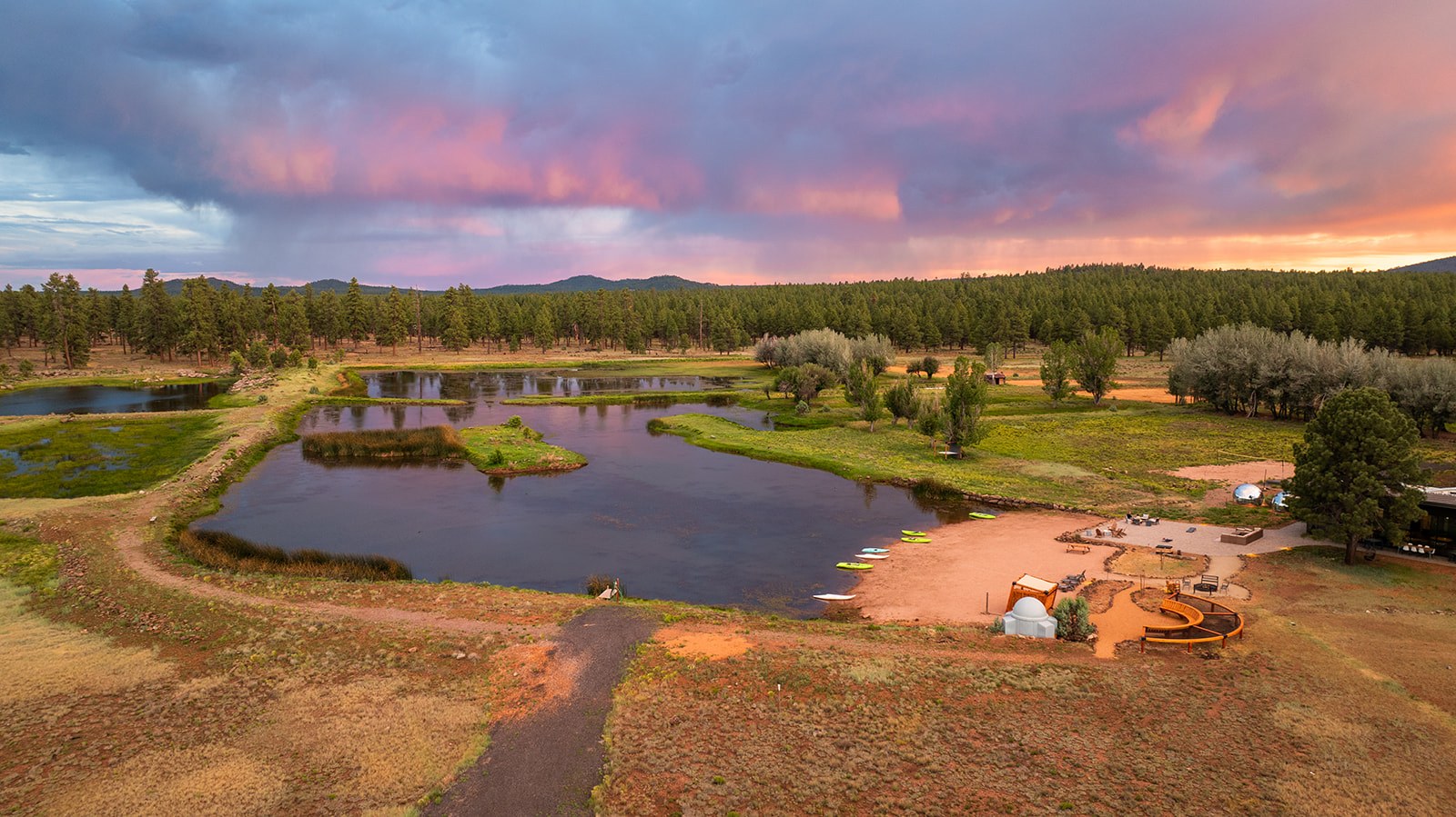 Aerial view of Backland Luxury Nature Resort and its pond beneath a vivid Arizona sunset