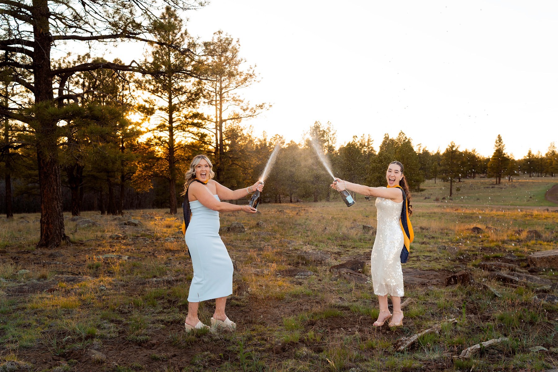 Jade and Maya celebrating their NAU graduation outdoors in Flagstaff