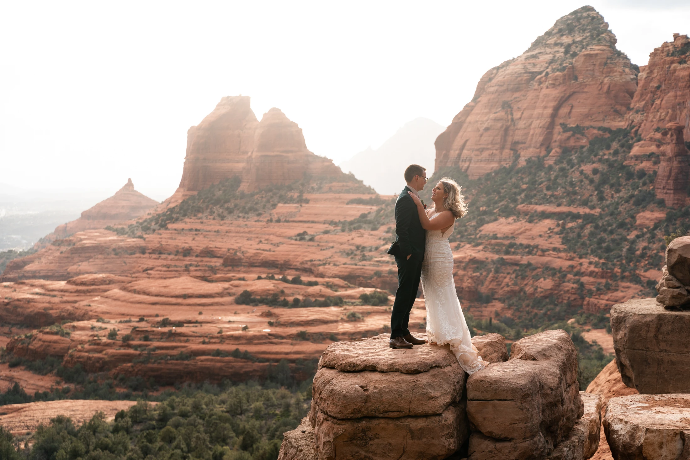 Stephanie and Nathan sharing a kiss overlooking the red rock formations at Merry-Go-Round Rock
